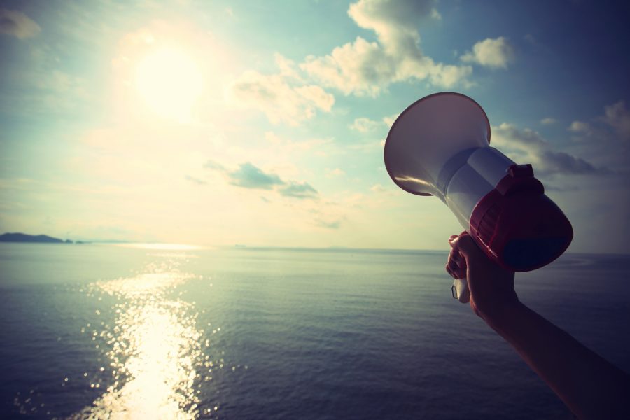 hands hold megaphone with sea under blue sky background